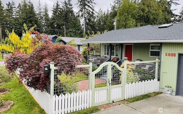 1403 Thomas St, Port Townsend, WA 98368 - view of front facade featuring a shingled roof, a fenced front yard, a gate, and view of scattered trees