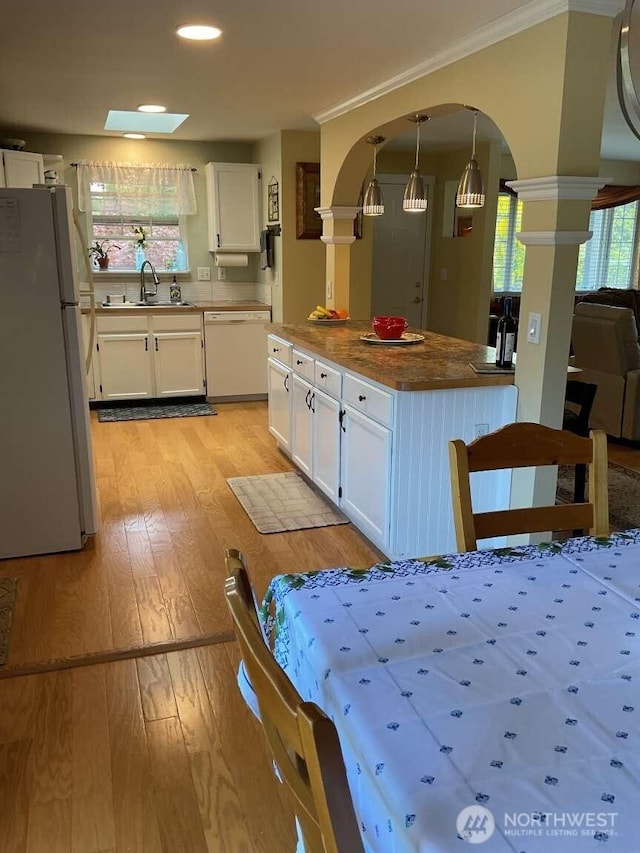 1403 Thomas St, Port Townsend, WA 98368 - kitchen with white appliances, a sink, light wood-style floors, arched walkways, and white cabinets