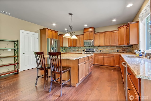 9440 Piperhill Dr SE, Olympia, WA 98513 - kitchen featuring stainless steel appliances, a sink, dark wood-style floors, light stone counters, and a kitchen breakfast bar