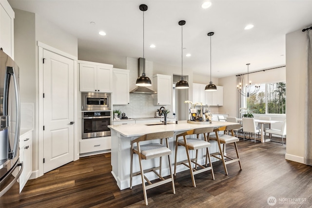 10610 134th Dr NE Unit 111, Lake Stevens, WA 98258 - kitchen featuring stainless steel appliances, wall chimney range hood, dark wood-style floors, backsplash, and a breakfast bar area