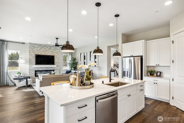 10610 134th Dr NE Unit 111, Lake Stevens, WA 98258 - kitchen featuring appliances with stainless steel finishes, a sink, a ceiling fan, a stone fireplace, and dark wood-style flooring