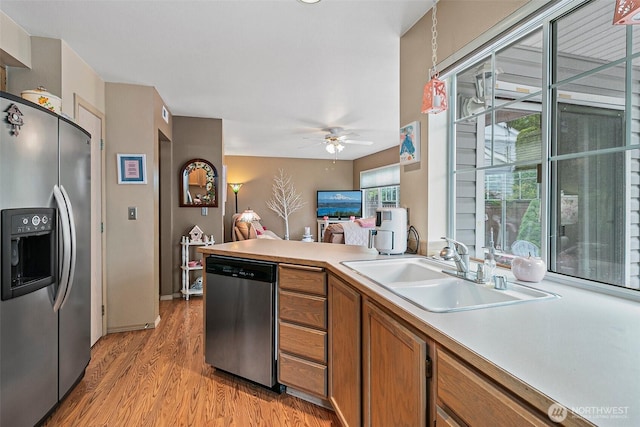 7608 145th Avenue Ct E, Sumner, WA 98390 - kitchen with stainless steel appliances, a sink, brown cabinets, light wood-style flooring, and a ceiling fan