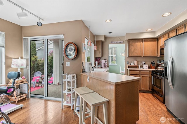7608 145th Avenue Ct E, Sumner, WA 98390 - kitchen featuring appliances with stainless steel finishes, a peninsula, light countertops, rail lighting, and light wood-style flooring