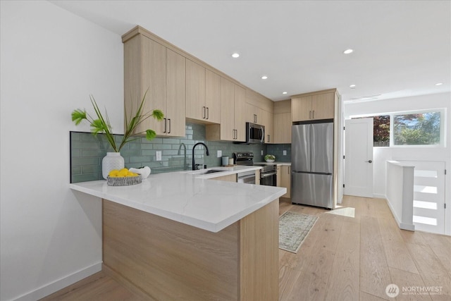 6032 42nd Ave SW Unit C, Seattle, WA 98136 - kitchen with stainless steel appliances, light brown cabinets, a peninsula, light wood-type flooring, and tasteful backsplash