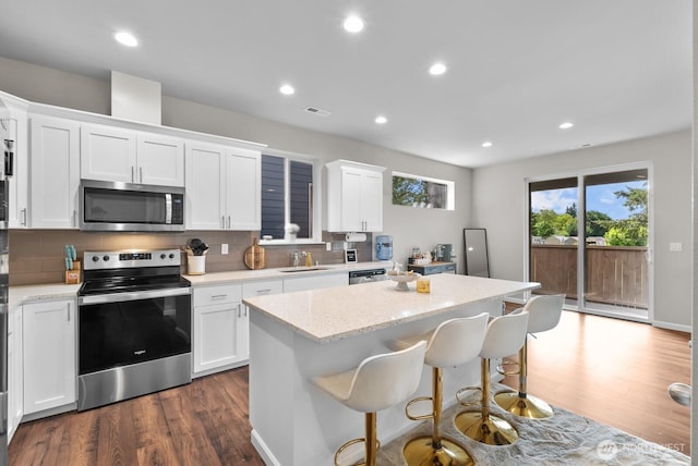 3808 181st St E, Tacoma, WA 98446 - kitchen with stainless steel appliances, a sink, a kitchen island, dark wood-style flooring, and recessed lighting