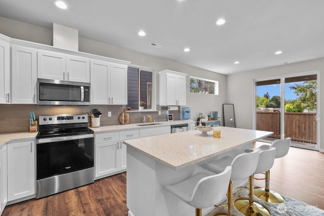 3808 181st St E, Tacoma, WA 98446 - kitchen with appliances with stainless steel finishes, a sink, dark wood-style flooring, a center island, and white cabinets