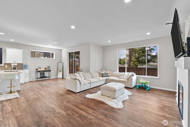 3808 181st St E, Tacoma, WA 98446 - living area with a glass covered fireplace, recessed lighting, light wood-type flooring, and baseboards