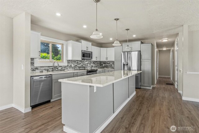 6015 NW Perthshire Rd, Vancouver, WA 98663 - kitchen featuring appliances with stainless steel finishes, a sink, dark wood finished floors, decorative backsplash, and baseboards