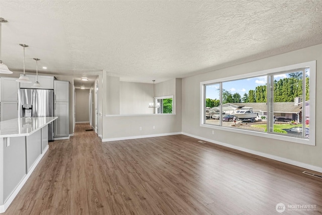 6015 NW Perthshire Rd, Vancouver, WA 98663 - unfurnished living room featuring wood finished floors, baseboards, and a textured ceiling