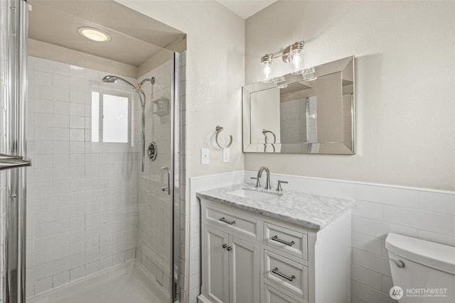 6015 NW Perthshire Rd, Vancouver, WA 98663 - bathroom with a shower stall, vanity, toilet, a wainscoted wall, and tile walls