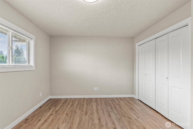 6015 NW Perthshire Rd, Vancouver, WA 98663 - unfurnished bedroom with light wood finished floors, a closet, baseboards, and a textured ceiling