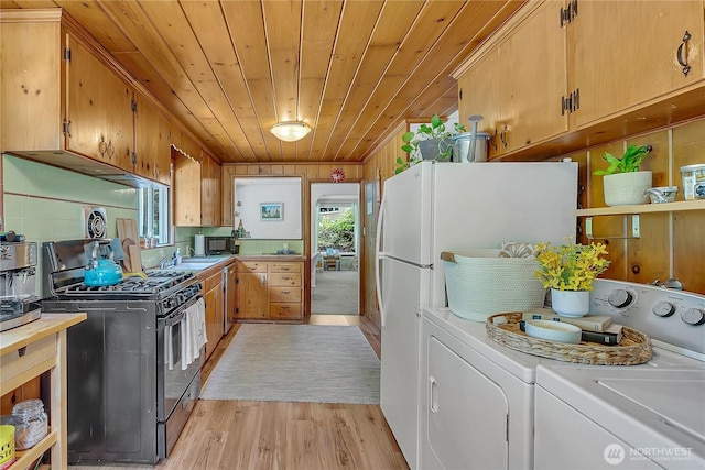 9024 29th St W, University Place, WA 98466 - kitchen featuring black appliances, independent washer and dryer, wood ceiling, plenty of natural light, and light wood finished floors