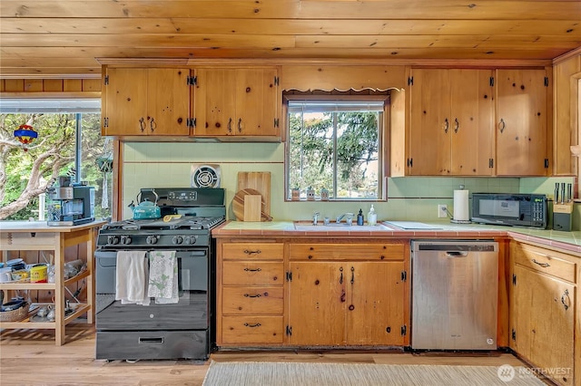 9024 29th St W, University Place, WA 98466 - kitchen featuring black appliances, wood ceiling, tile countertops, a sink, and plenty of natural light