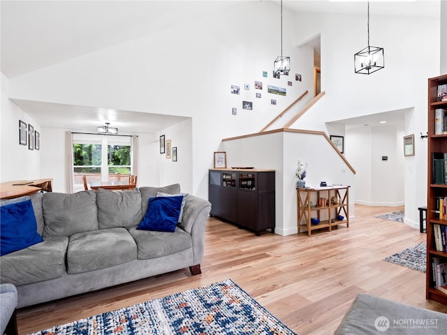 8221 122nd Ave NE, Kirkland, WA 98033 - living room featuring high vaulted ceiling, a chandelier, light wood-style floors, and baseboards