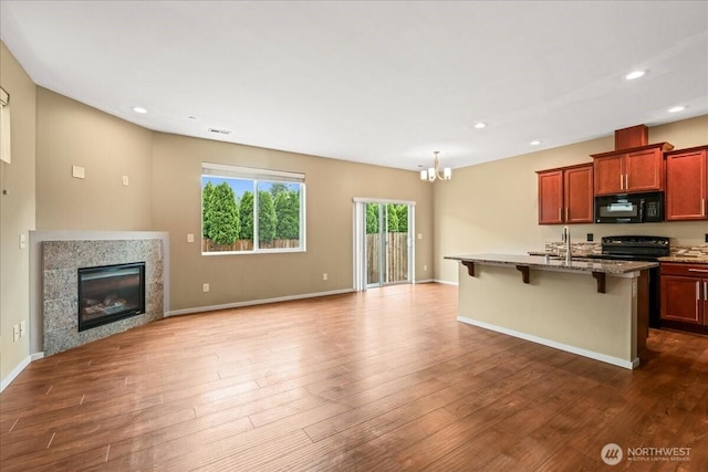 21421 104th Street Ct E, Bonney Lake, WA 98391 - kitchen with black microwave, open floor plan, electric range oven, a chandelier, and a kitchen bar