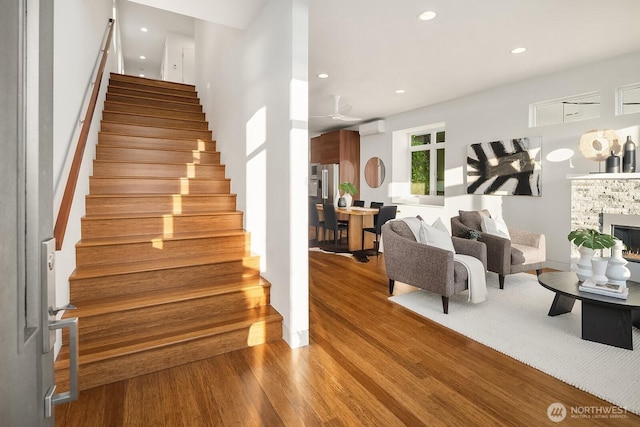 2222 Broadway E, Seattle, WA 98102 - staircase featuring wood finished floors, a wall mounted AC, a stone fireplace, and recessed lighting