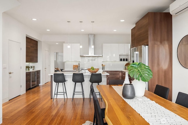2222 Broadway E, Seattle, WA 98102 - kitchen with wall chimney range hood, modern cabinets, beverage cooler, light countertops, and a wall unit AC