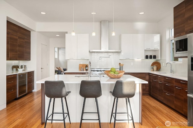 2222 Broadway E, Seattle, WA 98102 - kitchen with modern cabinets, beverage cooler, wall chimney exhaust hood, a sink, and a breakfast bar