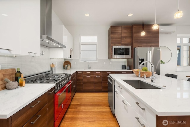 2222 Broadway E, Seattle, WA 98102 - kitchen featuring appliances with stainless steel finishes, wall chimney range hood, a sink, modern cabinets, and an AC wall unit