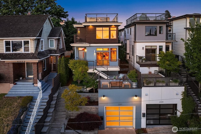 2222 Broadway E, Seattle, WA 98102 - back of property at dusk with a garage, stairway, and a balcony