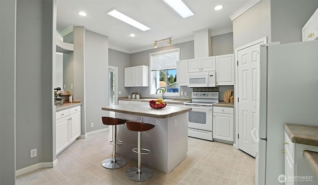 6614 241st Ave E Unit 38, Buckley, WA 98321 - kitchen with white appliances, ornamental molding, white cabinetry, a breakfast bar area, and recessed lighting