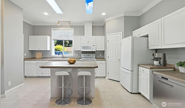 6614 241st Ave E Unit 38, Buckley, WA 98321 - kitchen featuring white appliances, crown molding, white cabinetry, a breakfast bar area, and a center island