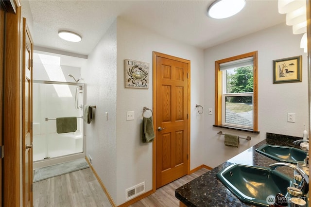 21806 168th St E, Orting, WA 98360 - bathroom with wood finished floors, a stall shower, double vanity, and a textured ceiling