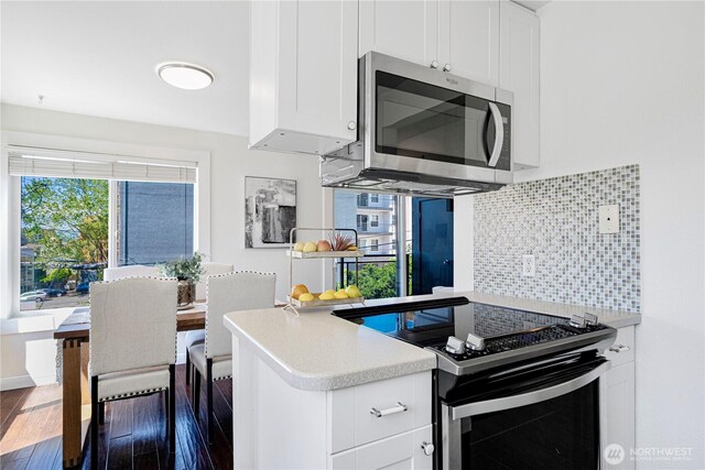 613 4th Ave W Unit 202, Seattle, WA 98119 - kitchen featuring stainless steel microwave, electric range oven, backsplash, white cabinets, and light countertops