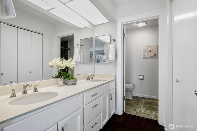 613 4th Ave W Unit 202, Seattle, WA 98119 - full bathroom with double vanity, toilet, wood finished floors, and baseboards