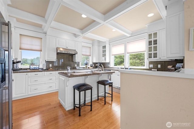 234 26th St NW, Long Beach, WA 98631 - kitchen featuring a breakfast bar area, tasteful backsplash, white cabinets, beamed ceiling, and glass insert cabinets