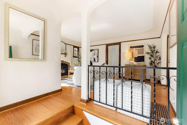 1214 NE 98th St, Seattle, WA 98115 - staircase featuring a glass covered fireplace, wood finished floors, arched walkways, and baseboards