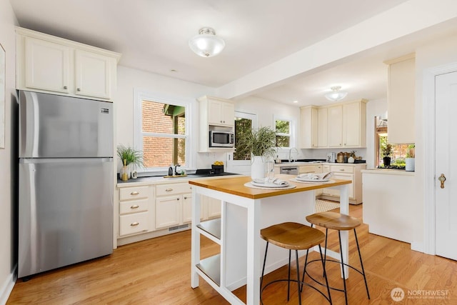 1214 NE 98th St, Seattle, WA 98115 - kitchen featuring stainless steel appliances, a breakfast bar, light wood-type flooring, a center island, and a sink