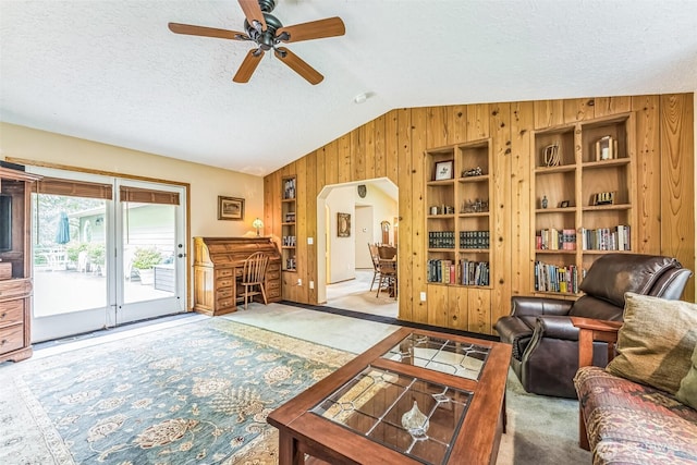3220 N Pacific Ave, Kelso, WA 98626 - carpeted living area featuring wood walls, a textured ceiling, ceiling fan, vaulted ceiling, and arched walkways