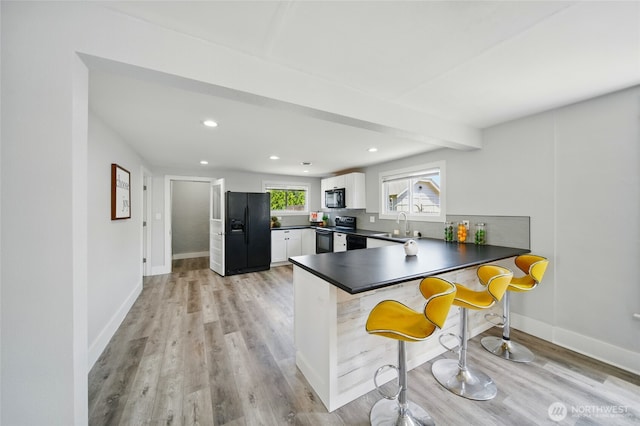 1128 W Elm St, Walla Walla, WA 99362 - kitchen featuring black appliances, dark countertops, a sink, a peninsula, and white cabinetry