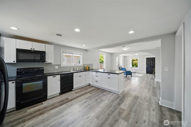 1128 W Elm St, Walla Walla, WA 99362 - kitchen featuring black appliances, arched walkways, a peninsula, a sink, and dark countertops