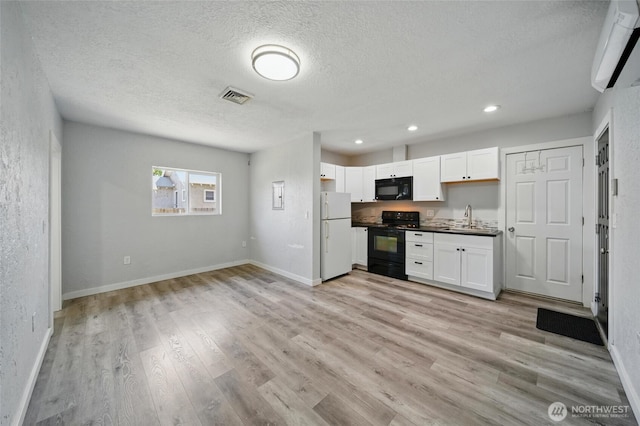 1128 W Elm St, Walla Walla, WA 99362 - kitchen with black appliances, a sink, a textured ceiling, light wood-type flooring, and white cabinets
