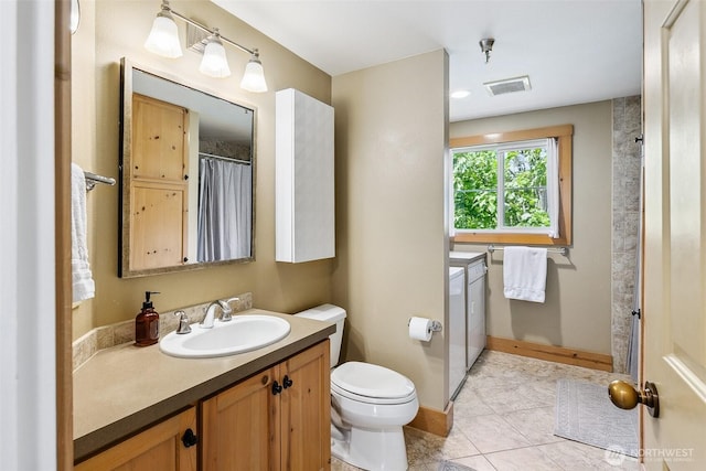 490 Madison Ave N Unit 202, Bainbridge Island, WA 98110 - bathroom with washing machine and clothes dryer, vanity, toilet, tile patterned flooring, and baseboards