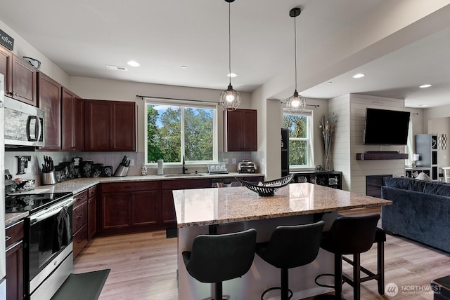 2225 Seringa Ave, Bremerton, WA 98310 - kitchen with stainless steel appliances, open floor plan, a sink, a center island, and light wood finished floors