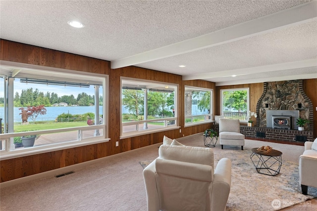 16801 Lakeside Dr S, Spanaway, WA 98387 - carpeted living room with a textured ceiling, wood walls, beamed ceiling, a water view, and a fireplace