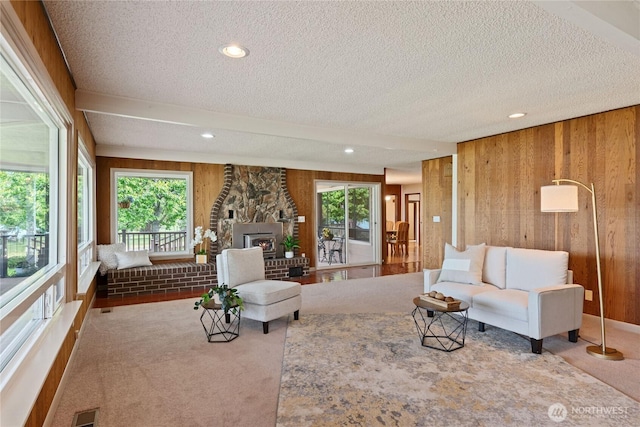 16801 Lakeside Dr S, Spanaway, WA 98387 - living room with wood walls, a textured ceiling, carpet, a stone fireplace, and recessed lighting