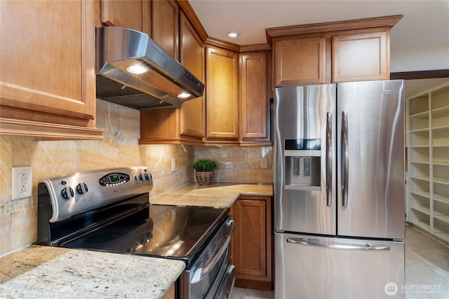 16801 Lakeside Dr S, Spanaway, WA 98387 - kitchen with appliances with stainless steel finishes, under cabinet range hood, brown cabinetry, light stone counters, and recessed lighting