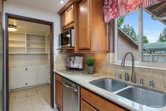 16801 Lakeside Dr S, Spanaway, WA 98387 - kitchen featuring a sink, stainless steel appliances, brown cabinetry, backsplash, and light stone countertops