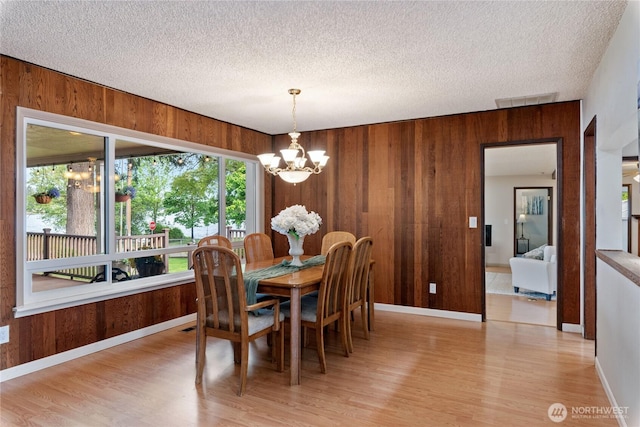 16801 Lakeside Dr S, Spanaway, WA 98387 - dining space featuring wooden walls, a chandelier, light wood-style floors, plenty of natural light, and a textured ceiling