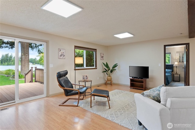 16801 Lakeside Dr S, Spanaway, WA 98387 - living area featuring healthy amount of natural light, a textured ceiling, wood finished floors, and a water view