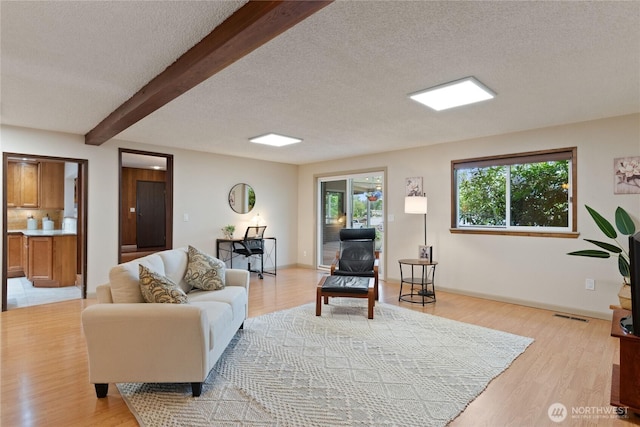 16801 Lakeside Dr S, Spanaway, WA 98387 - living room featuring light wood finished floors, beamed ceiling, a textured ceiling, and baseboards
