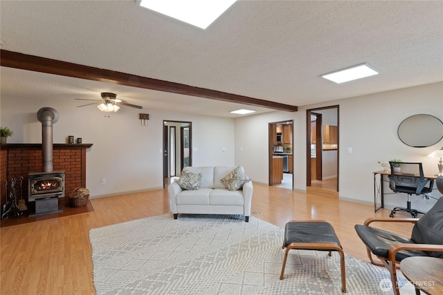 16801 Lakeside Dr S, Spanaway, WA 98387 - living area with light wood-type flooring, a wood stove, beam ceiling, a textured ceiling, and ceiling fan