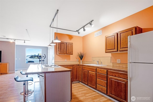 927 Pheasant Run, Westport, WA 98595 - kitchen with track lighting, white appliances, a sink, brown cabinetry, and light wood-type flooring