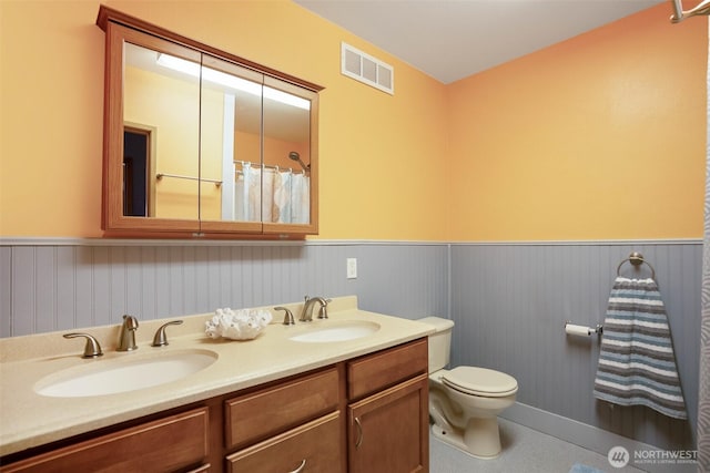 927 Pheasant Run, Westport, WA 98595 - bathroom featuring wainscoting, toilet, and double vanity