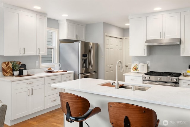 14819 1st Ave NE, Duvall, WA 98019 - kitchen with under cabinet range hood, appliances with stainless steel finishes, a sink, a breakfast bar, and recessed lighting