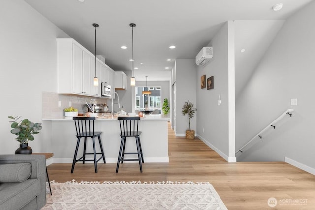 15726 40th Ave W Unit B3, Lynnwood, WA 98087 - kitchen featuring stainless steel microwave, an AC wall unit, a peninsula, light countertops, and white cabinetry